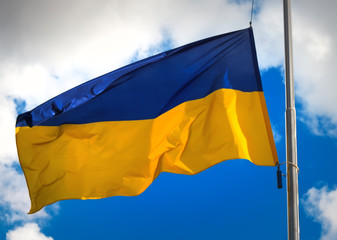 Flag of Ukraine against a blue cloudy sky.