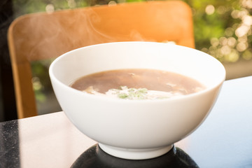 Hot soup and smoke in white bowl.