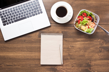 Workplace, healthy business lunch, salad, coffee on wooden table. Top view, copy space. Concept nutrition in office. To do list. Lunchbox.