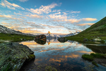 Obraz premium Morning shot of the golden Matterhorn (Monte Cervino, Mont Cervin) pyramid and blue Stellisee lake. Sunrise view of majestic mountain landscape.