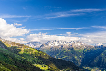 Scenic view of beautiful landscape in Swiss Alps. Fresh green meadows and snow-capped mountain tops in the background in springtime, Switzerland.