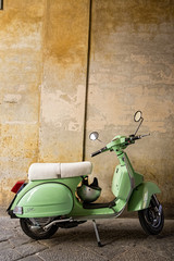 Green scooter parked under an archway in a street in Siena, Tuscany