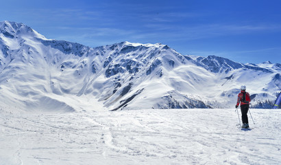 Fototapeta na wymiar skier on a slope in alpine snowy mountain under blue sky