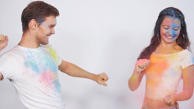 Young couple having fun with holi paints on a white background