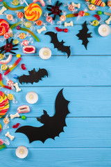 Assorted teeth and eyeball shaped candy spread on wooden table, jelly spider, gummy worms, round lollipop and other mixed candy on blue wood background. Top view, copy space, close up, flat lay.