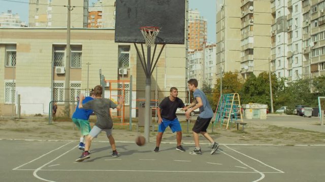 Offensive streetball team scoring field goal in the paint while playing basketball game on outdoor court. Baskteball player making successful assit to his teammate during streetball match ooutdoors.