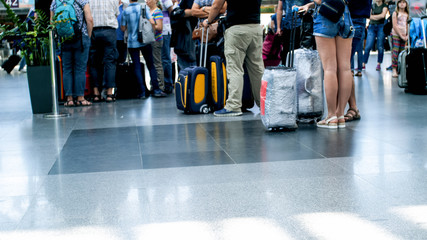 People feet and suitcase on floor at international airport terminal