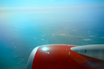 Naklejka na ściany i meble wing airplane view of sky / blue sky and wing of an airplane, view from the cabin of an airplane, concept of air transport