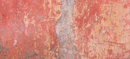 Old weathered painted wall background texture. Red dirty peeled plaster wall with falling off flakes of paint.