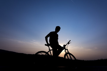 Silhouette of boy on the bike. Young cyclist is jumping on his bike during sunset.