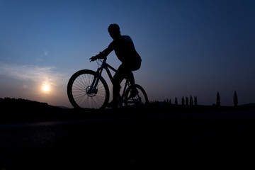 Silhouette of boy on the bike. Young cyclist is jumping on his bike during sunset.