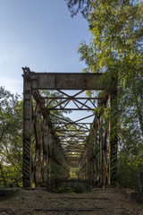 An old rusty cracked iron bridge without tracks across the river. Assignment from the Soviet Army.