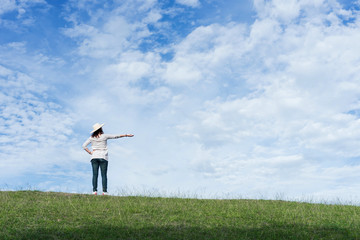 Woman standing on the mountain and point to beautiful sky.