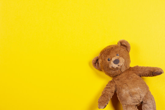 Naklejki Teddy bear toy on yellow background. Top view