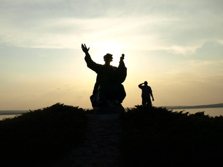 Obraz na płótnie Canvas Silhouette of a monument and man on sunset
