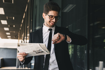Business man holding newspaper looking at watch clock.