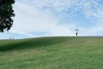 Fototapeta premium Standing woman raised her hands on the mountain, natural green and beautiful sky.