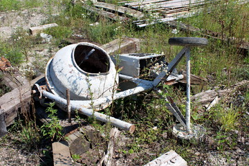 Heavily used broken and partially rusted electric concrete mixer with dried concrete all over metal...