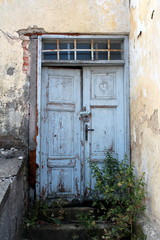 Light blue old dilapidated wooden doors locked with small padlock with windows above secured with...