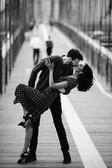 Love story in New York. Man and exotic woman dance with passion on the street with Brooklyn bridge...