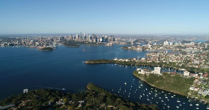 Going down towards green parks and reserve in local residential suburb Mosman on shores of Sydney harbour with city CBD landmarks.

