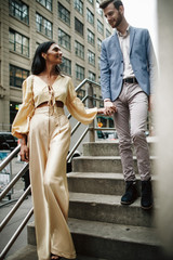 Love story in New York. Indian woman in bright yellow clothes and handsome American man hold each other hands walking around the New York