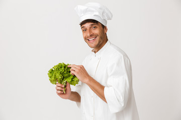 Happy young chef isolated over white background holding salad.