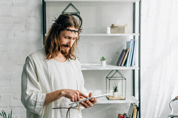 selective focus of Jesus in crown of thorns and robe using digital tablet at home