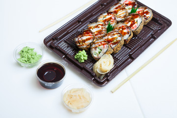Japanese food rolls in plastic box. Sushi set in a plastic package close up isolated on a white background. Sushi for take away or sushi delivery.