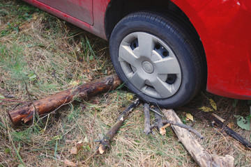 Fototapeta na wymiar Wheel of a red car. Accident in the woods, wooden sticks for traction with soil.