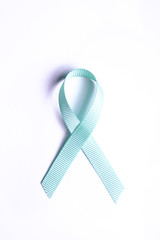 Blue awareness ribbon - symbol for fighting prostate cancer, support the survivors and child abuse awareness. Isolated on white background, copy space, close up, top view, flat lay.