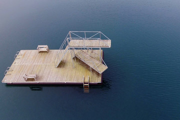 Wooden diving tower in the middle of the sea or lake. Aerial photograph with space for text.