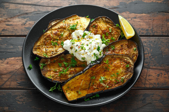 Healthy vegeterain Oven baked aubergines, Eggplant with cottage cheese dip, parsley and lemon wedge.