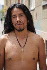 City portrait of young latino man with long hair and jewelry