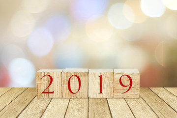 2019 new year greeting card, wooden cubes with 2019 on wood table over blur bokeh background with copy space for text, new year template