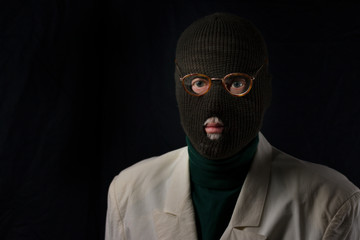 portrait of senior retired burglar wearing a ski mask on black background
