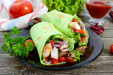 Burrito with chicken, vegetables, mushrooms in pita bread with spinach on a wooden table. Mexican food.