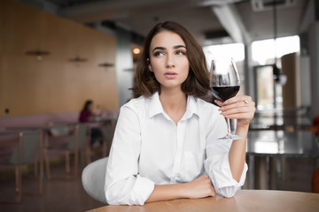 Young woman holding red wine glass sitting in the restaurant