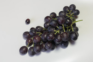 Branch of a red grape on the white background. Vegan food.