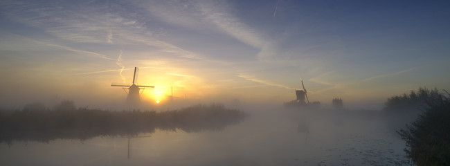 Fototapeta na wymiar Early morning mist on an autumn morning in the Kinderdijk UNESCO Heritage centre of windmills near Rottterdam, Netherlands