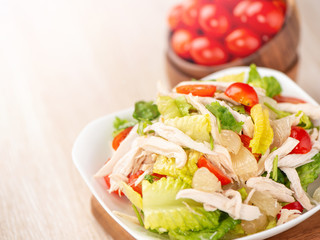 Fresh and delicious homemade chicken salad with tomatoes and pomelos in wooden background, concept of healthy and diet, top view, copy space