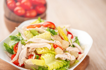 Fresh and delicious homemade chicken salad with tomatoes and pomelos in wooden background, concept of healthy and diet, top view, copy space