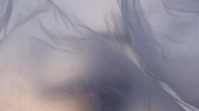 Slow Motion Shot Of A Blurred Image Of A Woman Behind Plastic Foil Waving In The Wind At Sunset