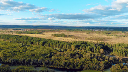 Naklejka premium Flight in the beautiful countryside among a river of woods and fields near the city