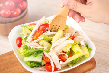 Fresh and delicious homemade chicken salad with tomatoes and pomelos in wooden background, concept of healthy and diet, top view, copy space