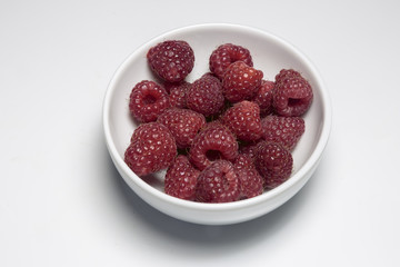Fresh raspberry in the bowl closeup.