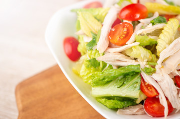 Fresh and delicious homemade chicken salad with tomatoes and pomelos in wooden background, concept of healthy and diet, top view, copy space
