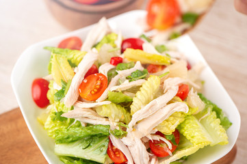 Fresh and delicious homemade chicken salad with tomatoes and pomelos in wooden background, concept of healthy and diet, top view, copy space