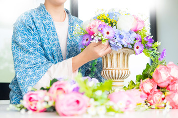 young women business owner florist making or Arranging Artificial flowers vest in her shop, craft and hand made concept