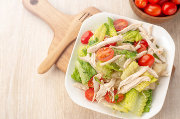 Fresh and delicious homemade chicken salad with tomatoes and pomelos in wooden background, concept of healthy and diet, top view, copy space